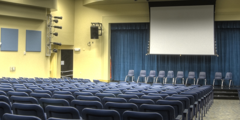 Empty auditorium hall at a school with well maintained auditorium chairs.